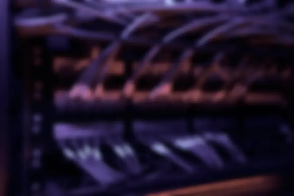 Structured network cabling running into a patch panel in a dark equipment room.